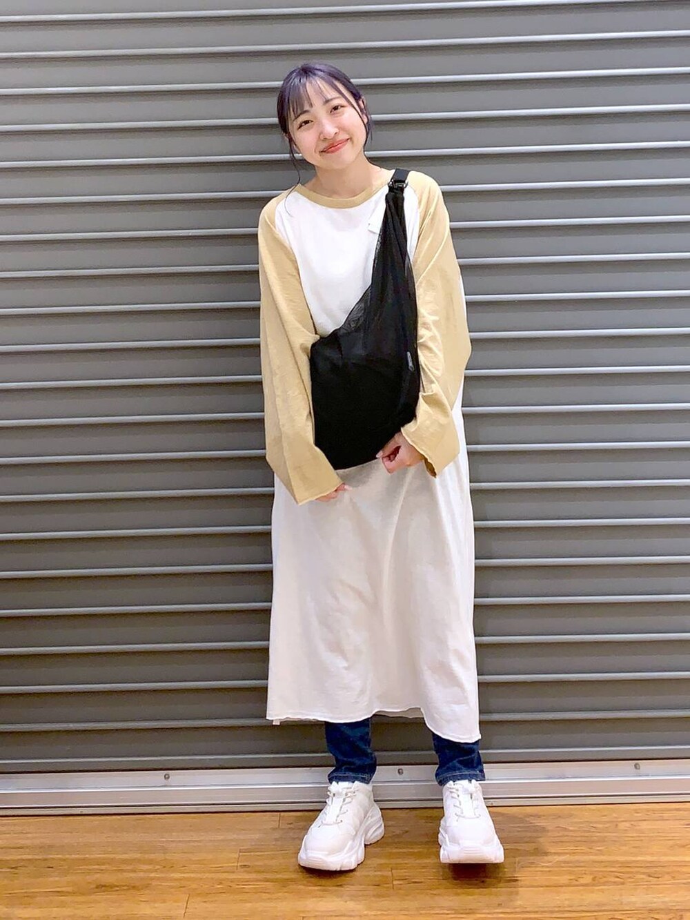 ベージュ系のワンピース、ホワイト系のスニーカー、ブルー系のデニムパンツを着用したレディースの春コーディネートの6枚目の写真