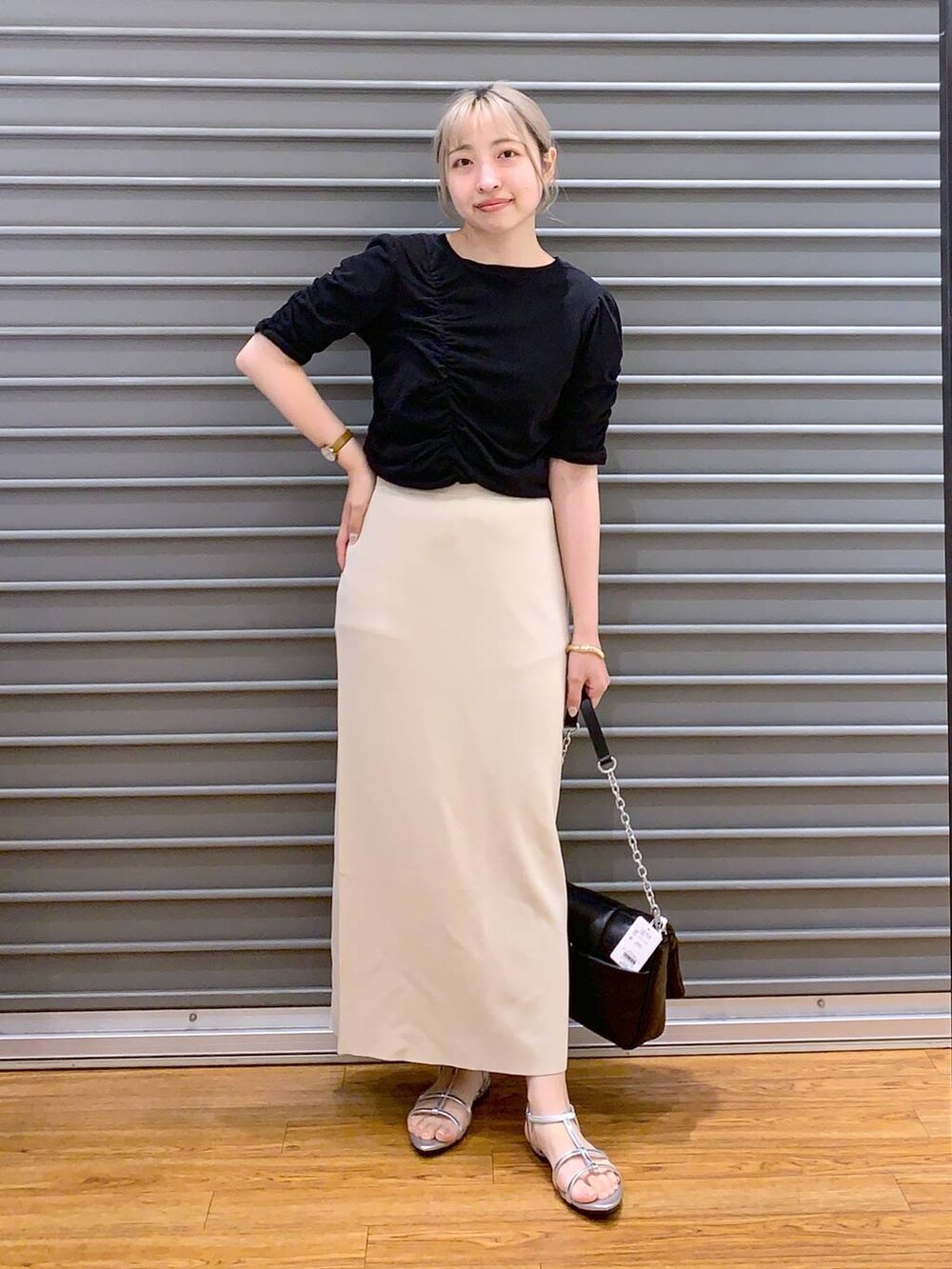 ブラック系のショルダーバッグ、ベージュ系のスカート、シルバー系のサンダルを着用したレディースの春コーディネートの5枚目の写真