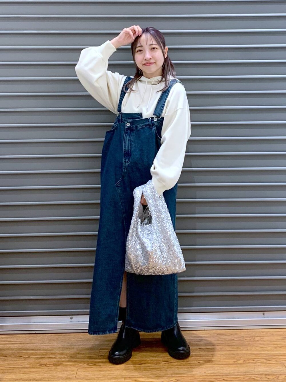 ブラック系のブーツ、ブルー系のジャンパースカート、ホワイト系のニット/セーターを着用したレディースの秋コーディネートの5枚目の写真