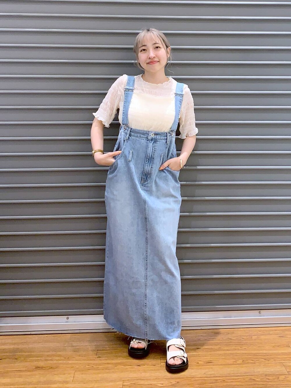 ホワイト系のショルダーバッグ、ホワイト系のキャミソール、ブルー系のジャンパースカートを着用したレディースの春コーディネートの3枚目の写真