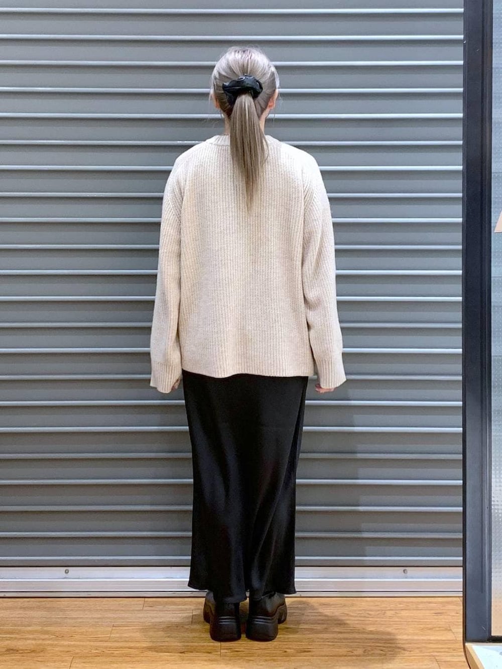 ブラック系のスカート、グリーン系のショルダーバッグ、ブラック系のブルゾンを着用したレディースの冬コーディネートの3枚目の写真