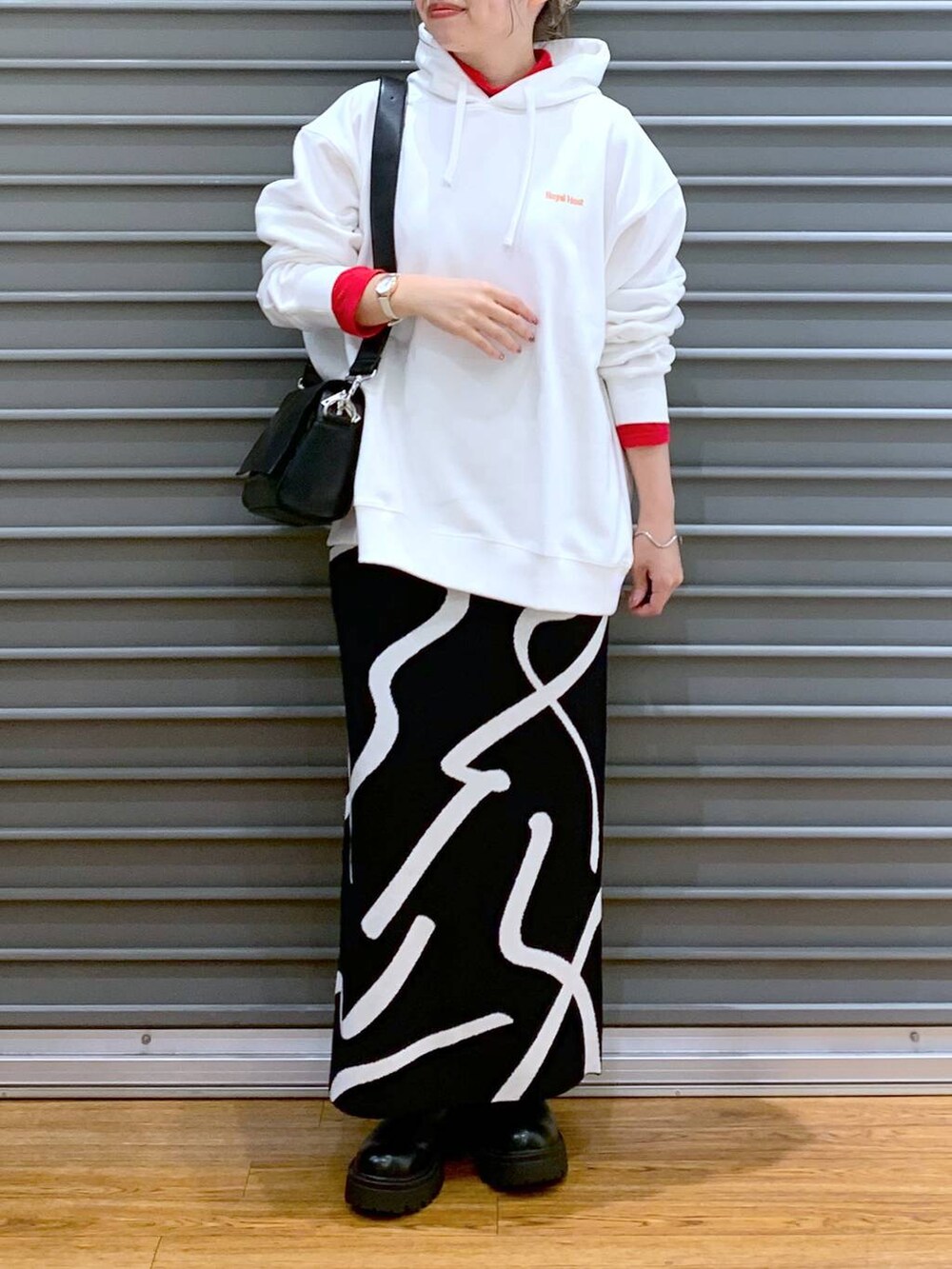 ブラック系のスカート、ブラック系のショルダーバッグ、ブラック系のブーツを着用したレディースの冬コーディネートの6枚目の写真