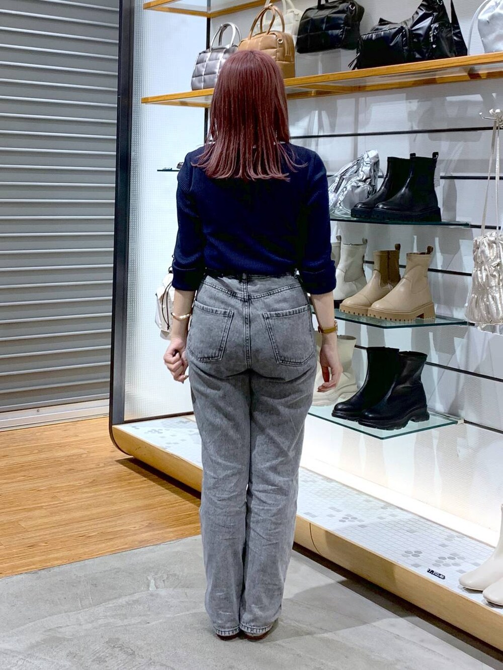 シルバー系のショルダーバッグ、シルバー系のパンプス、グレー系のデニムパンツを着用したレディースの秋コーディネートの2枚目の写真