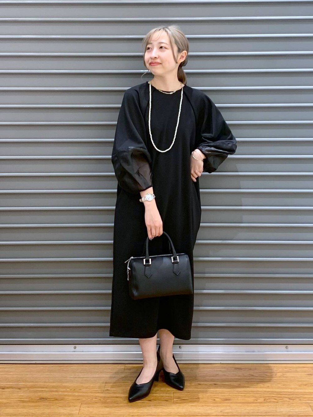 ブラック系のワンピース、ブラック系のパンプス、ブラック系のボストンバッグを着用したレディースの冬コーディネートの3枚目の写真