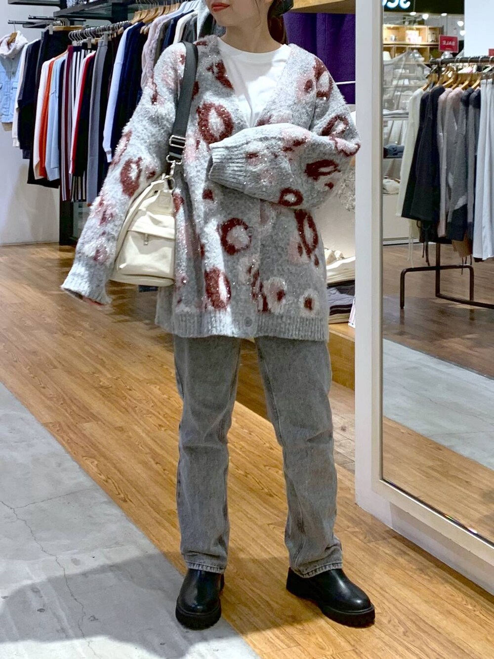 ブラック系のブーツ、グレー系のデニムパンツ、ホワイト系のショルダーバッグを着用したレディースの秋コーディネートの4枚目の写真