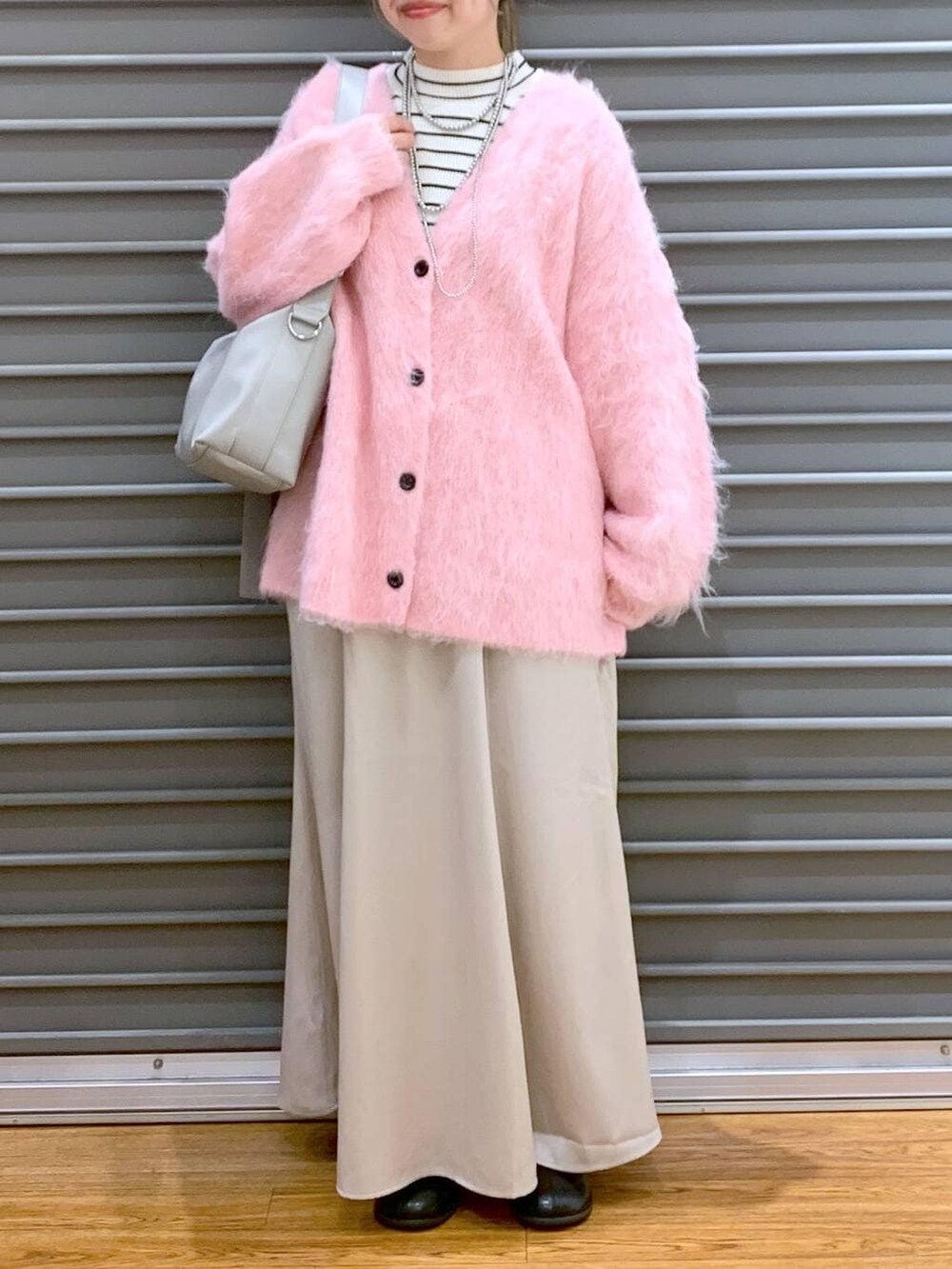 グレー系のショルダーバッグ、ホワイト系のニット/セーター、ブラック系のブーツを着用したレディースの冬コーディネートの6枚目の写真