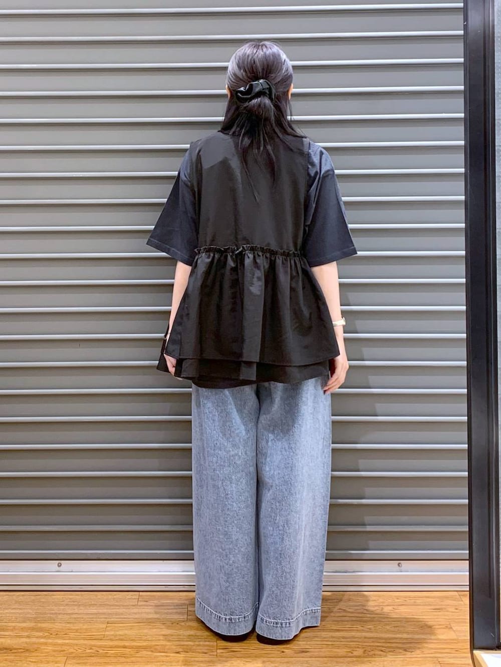 シルバー系のサンダル、ブルー系のデニムパンツ、ブラック系のベストを着用したレディースの夏コーディネートの2枚目の写真