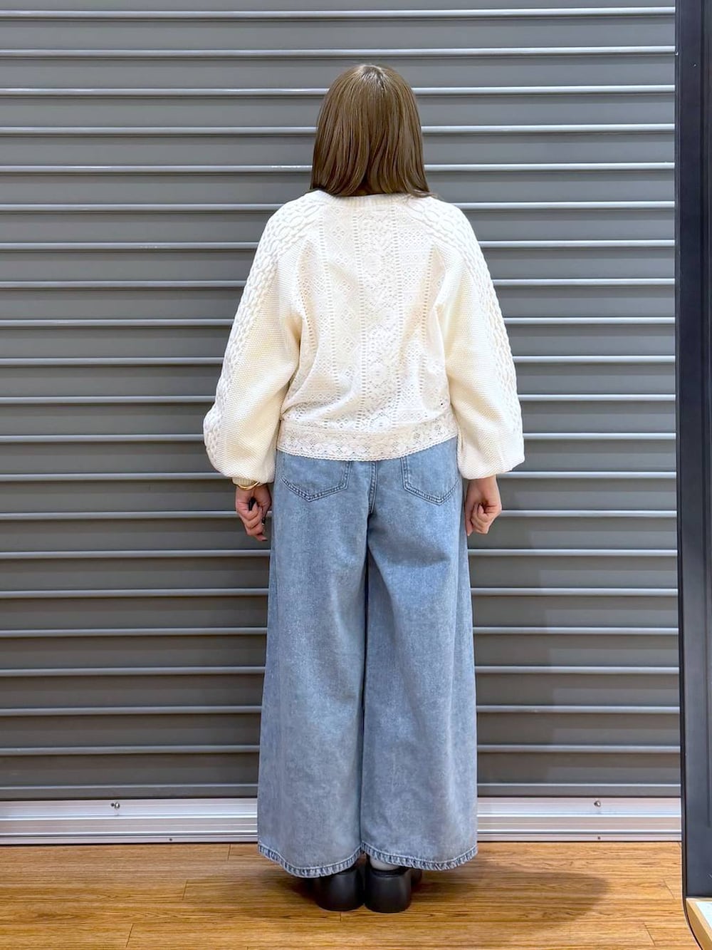 ブラック系のサンダル、ブルー系のデニムパンツ、ブラウン系のボストンバッグを着用したレディースの春コーディネートの2枚目の写真