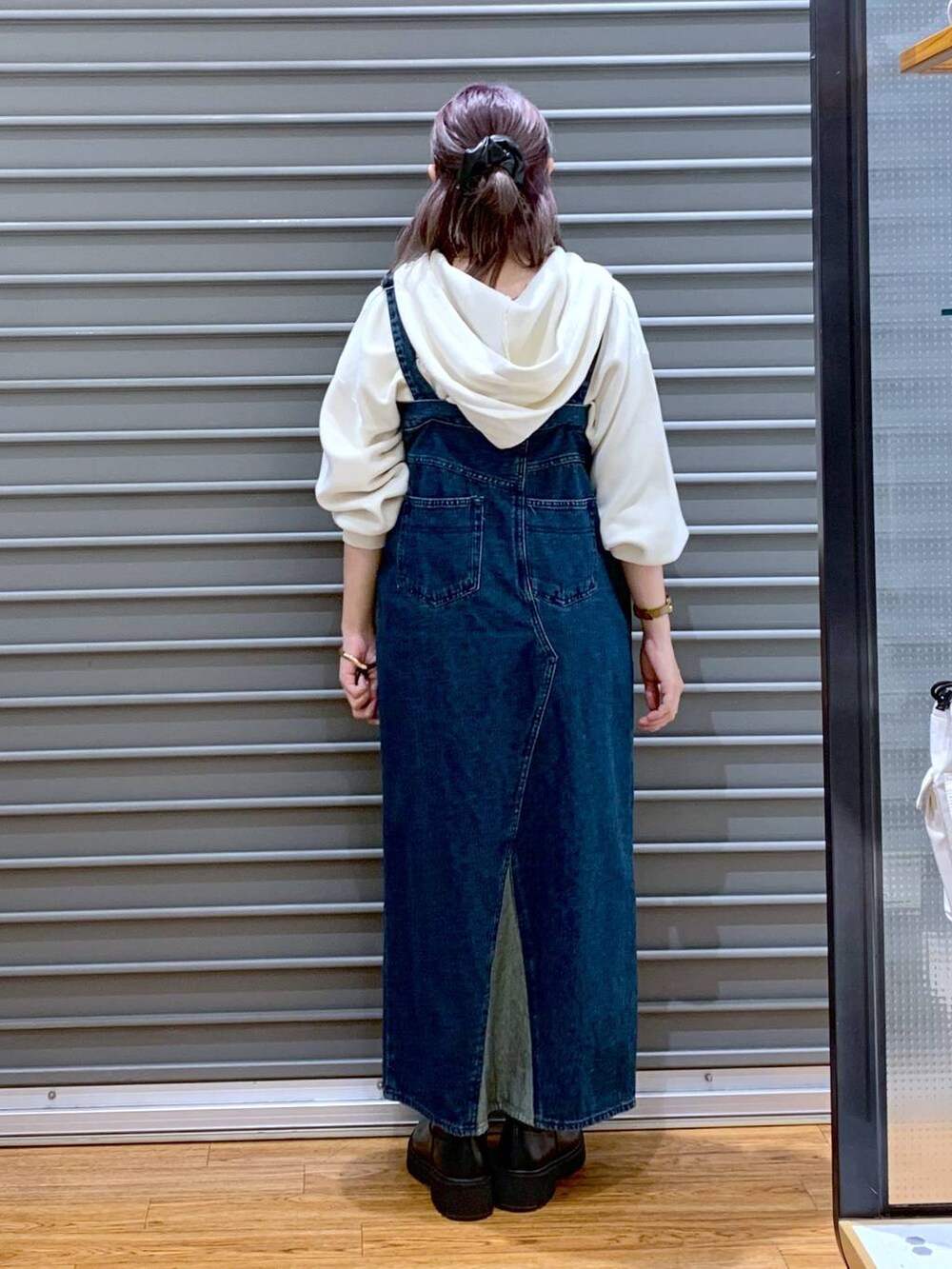 ブラック系のブーツ、ブルー系のジャンパースカート、ホワイト系のニット/セーターを着用したレディースの秋コーディネートの2枚目の写真