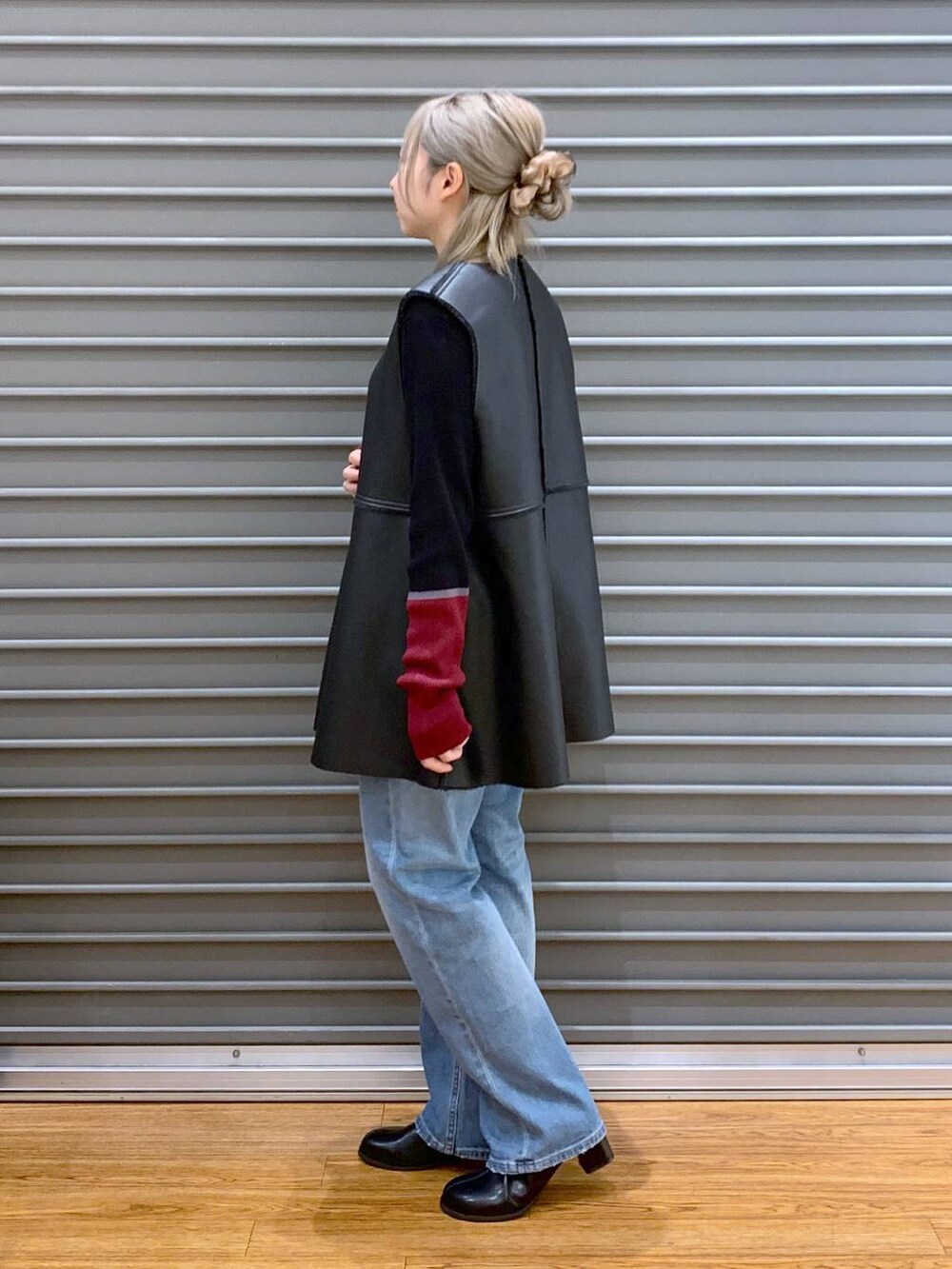 ブルー系のデニムパンツ、ブラック系のニット/セーター、ブラック系のショルダーバッグを着用したレディースの秋コーディネートの3枚目の写真