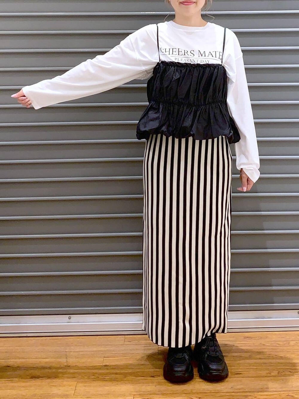 ブラック系のショルダーバッグ、ブラック系のスニーカー、ホワイト系のスカートを着用したレディースの春コーディネートの3枚目の写真