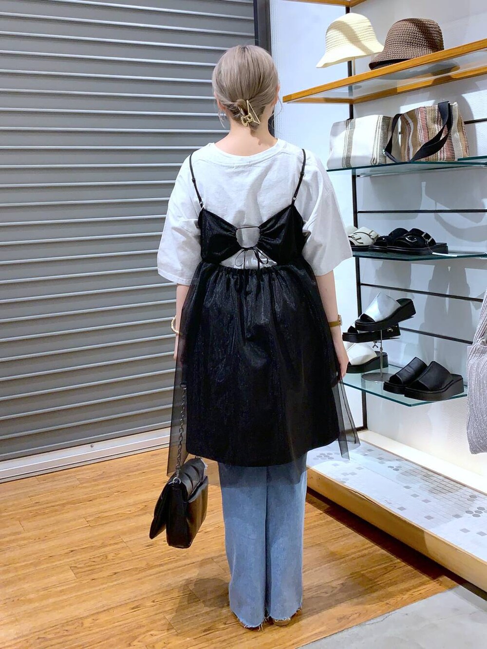 ブラック系のショルダーバッグ、ベージュ系のサンダル、ブルー系のデニムパンツを着用したレディースの夏コーディネートの2枚目の写真