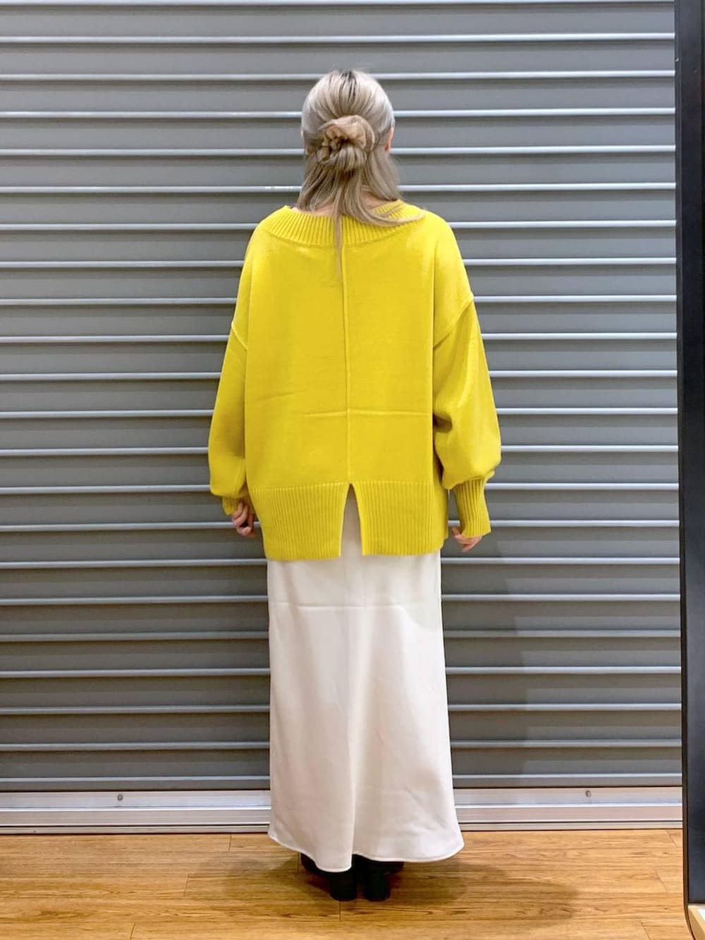 イエロー系のニット/セーター、ホワイト系のスカート、グレー系のショルダーバッグを着用したレディースの冬コーディネートの2枚目の写真