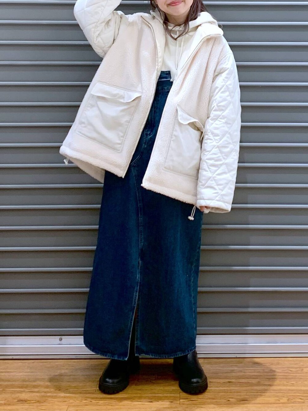 ホワイト系のショルダーバッグ、ブルー系のジャンパースカート、ブラック系のブーツを着用したレディースの冬コーディネートの4枚目の写真