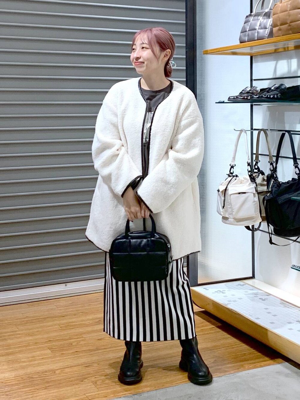 ブラック系のスカート、ホワイト系のその他アウター、ブラック系のボストンバッグを着用したレディースの秋コーディネートの4枚目の写真