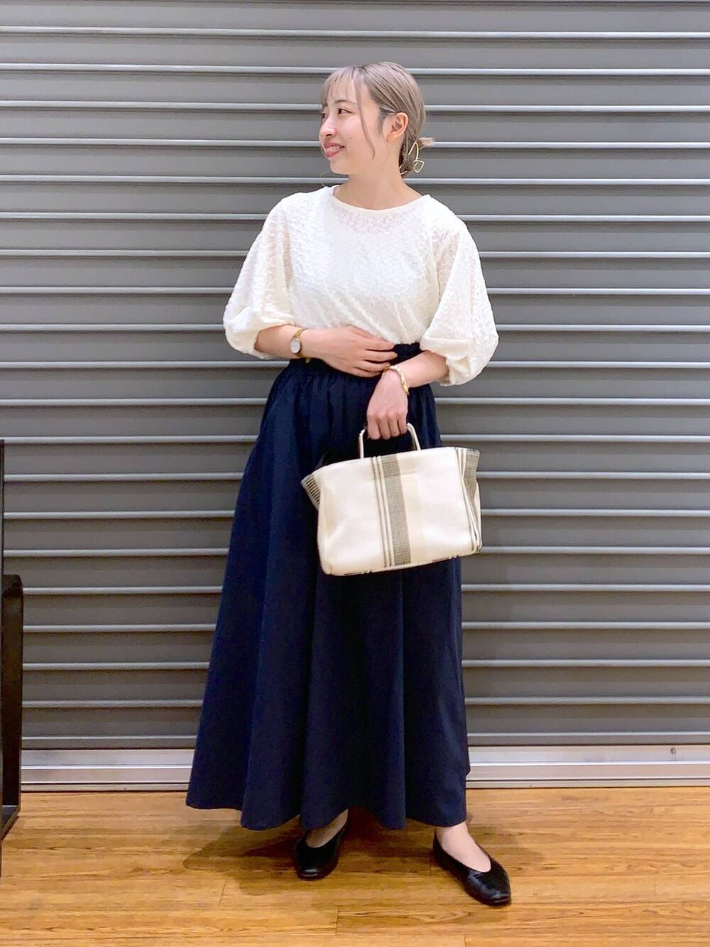 ホワイト系のショルダーバッグ、ブラック系のパンプス、ブルー系のスカートを着用したレディースの春コーディネートの4枚目の写真