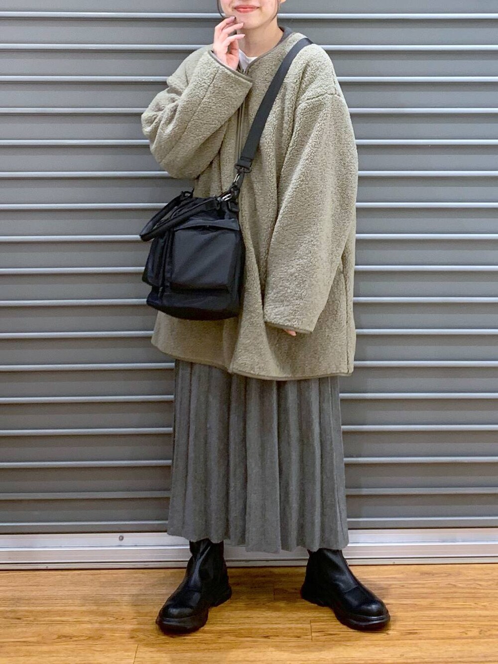 ブラック系のショルダーバッグ、グリーン系のその他アウター、ブラック系のブーツを着用したレディースの冬コーディネートの6枚目の写真