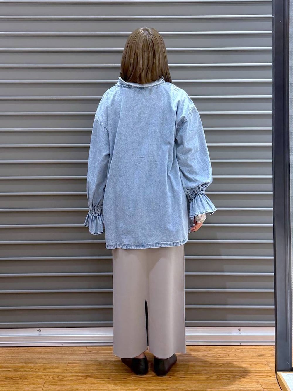 グレー系のスカート、ブラック系のパンプス、シルバー系のショルダーバッグを着用したレディースの春コーディネートの2枚目の写真