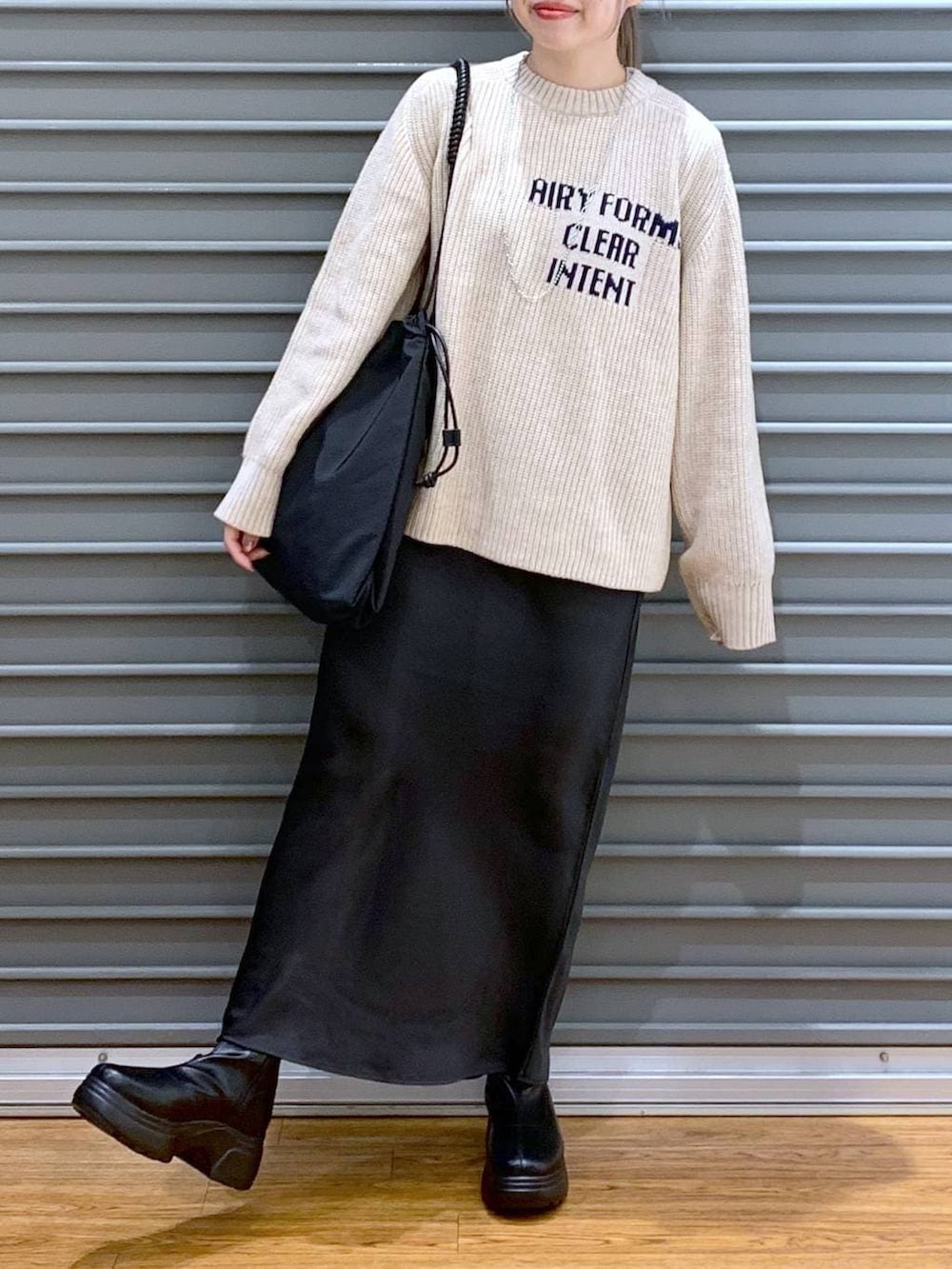 ブラック系のスカート、ブラック系のブーツ、ブラック系のトートバッグを着用したレディースの冬コーディネートの5枚目の写真