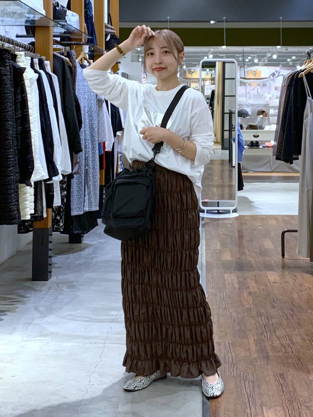 ブラック系のショルダーバッグ、ホワイト系のパンプス、イエロー系のスカートを着用したレディースの秋コーディネートの3枚目の写真