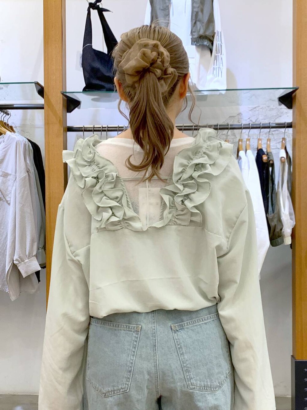 グリーン系のショルダーバッグ、ブルー系のデニムパンツ、ブラック系のサンダルを着用したレディースの春コーディネートの3枚目の写真