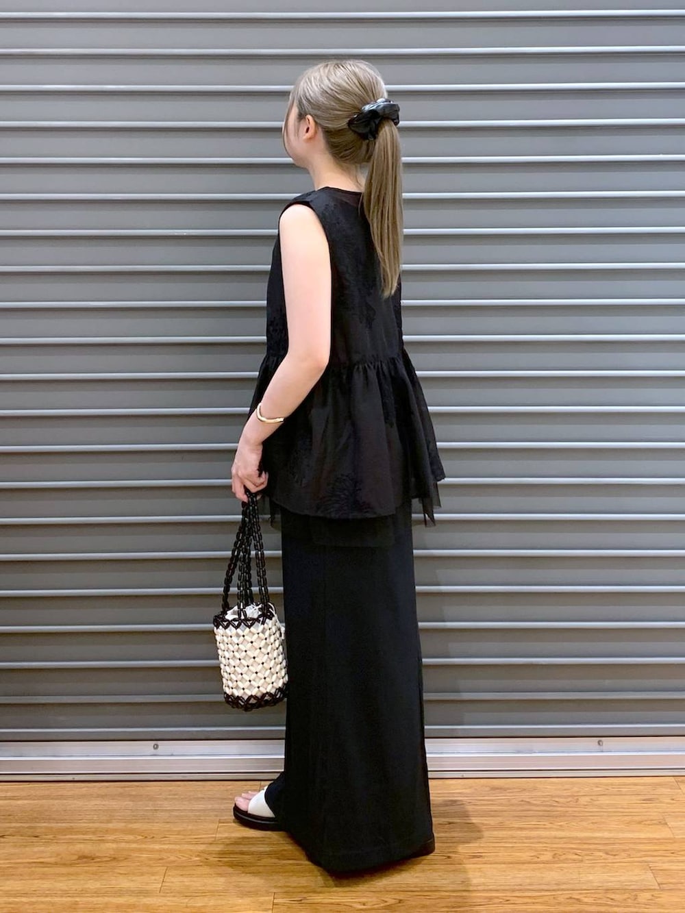 ホワイト系のサンダル、ホワイト系のハンドバッグ、ブラック系のシャツ/ブラウスを着用したレディースの夏コーディネートの3枚目の写真