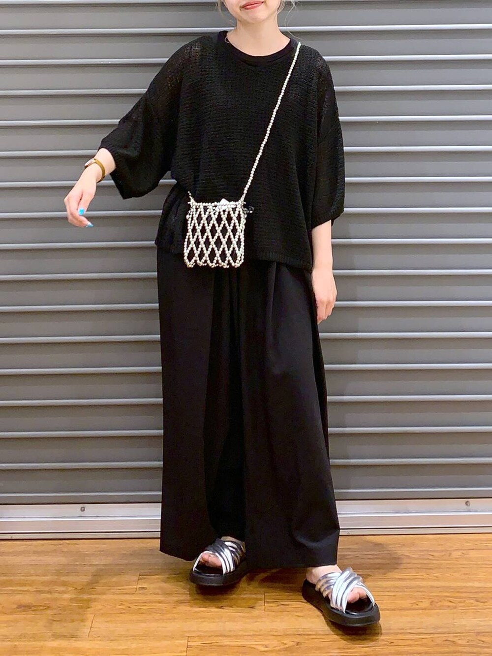 シルバー系のサンダル、ブラック系のスラックス、ブラック系のニット/セーターを着用したレディースの夏コーディネートの4枚目の写真