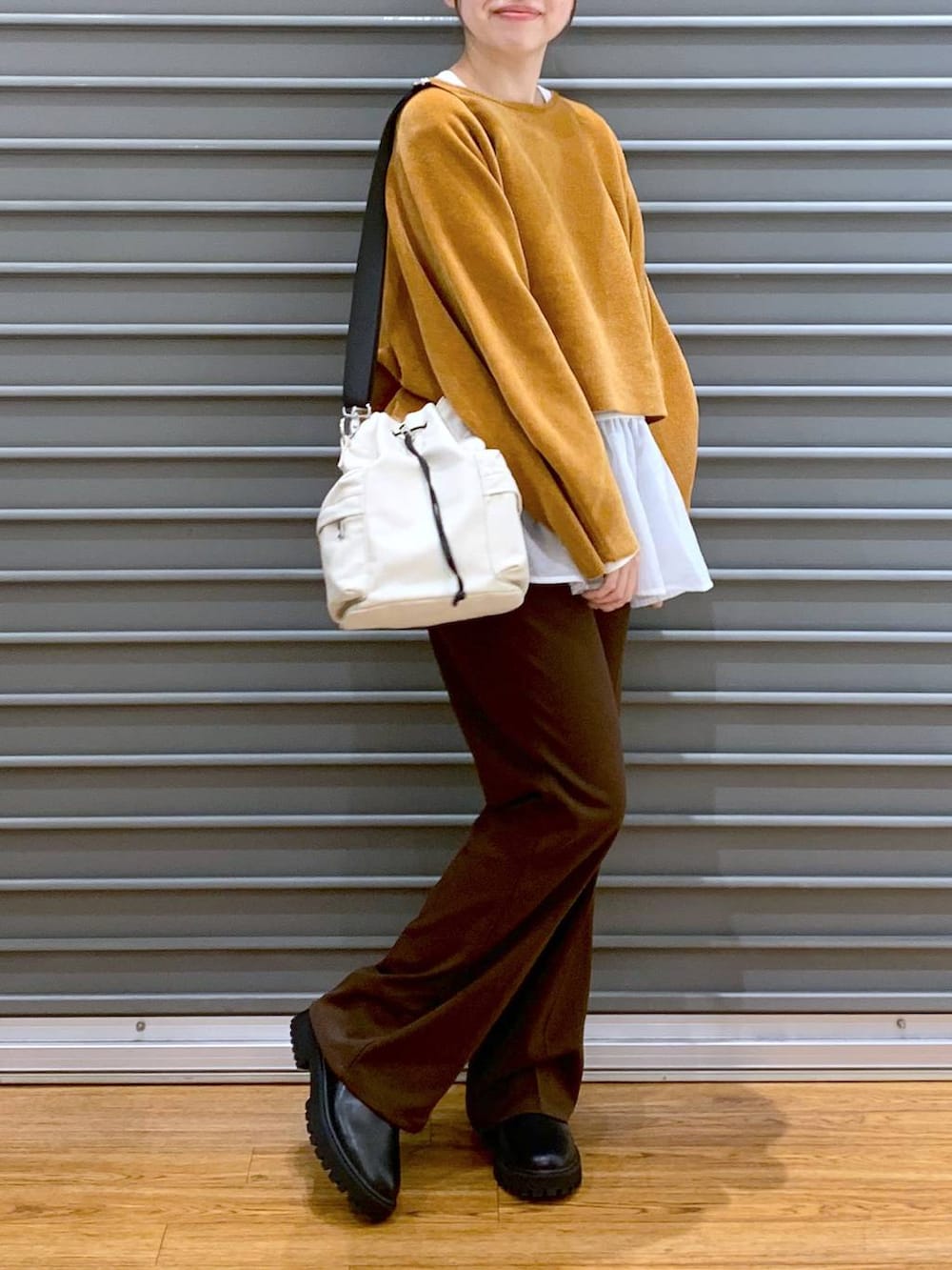 ブラック系のブーツ、ホワイト系のTシャツ/カットソー、ホワイト系のショルダーバッグを着用したレディースの冬コーディネートの3枚目の写真