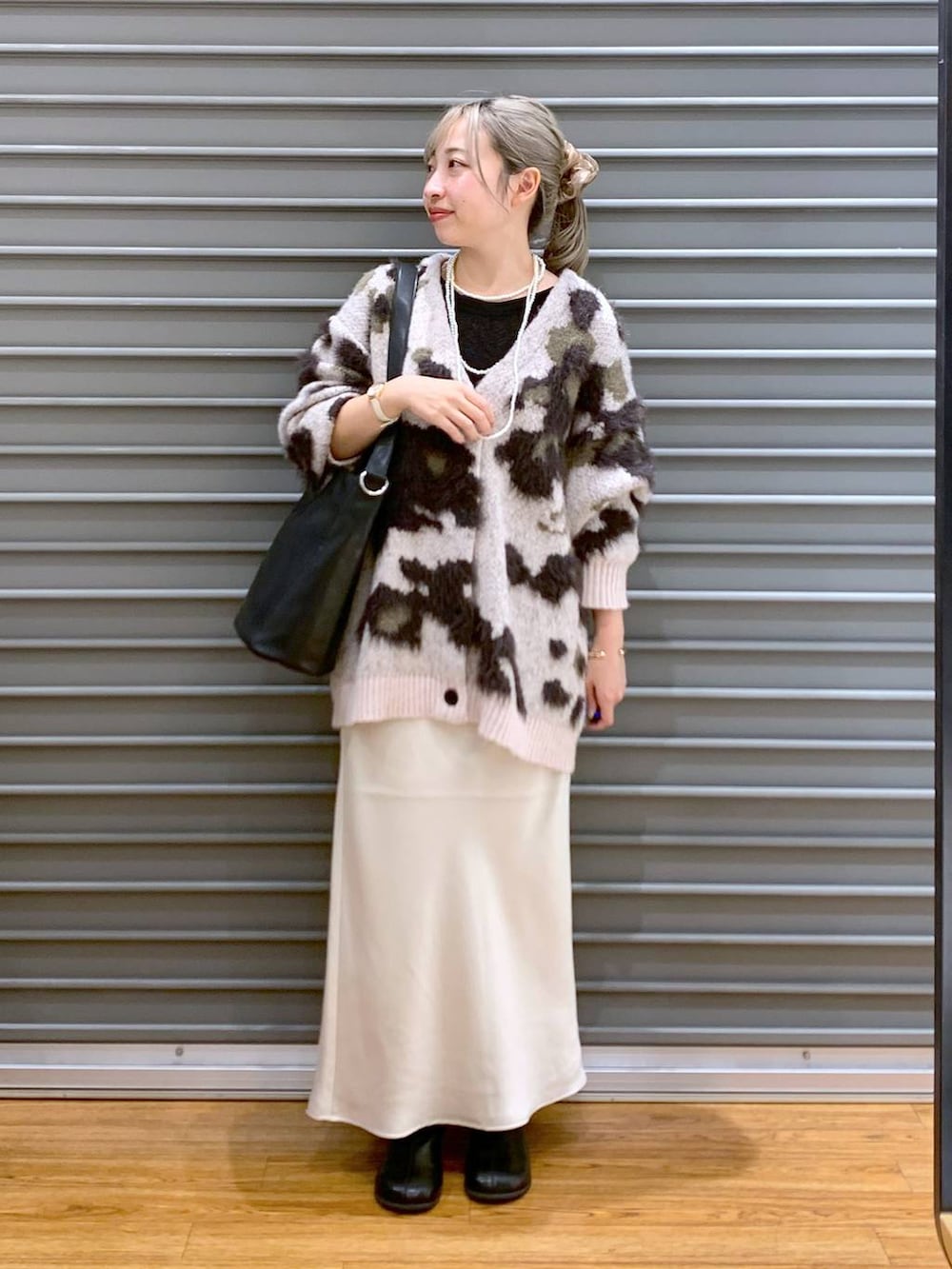 ホワイト系のスカート、ブラック系のショルダーバッグ、ブラック系のブーツを着用したレディースの冬コーディネートの6枚目の写真