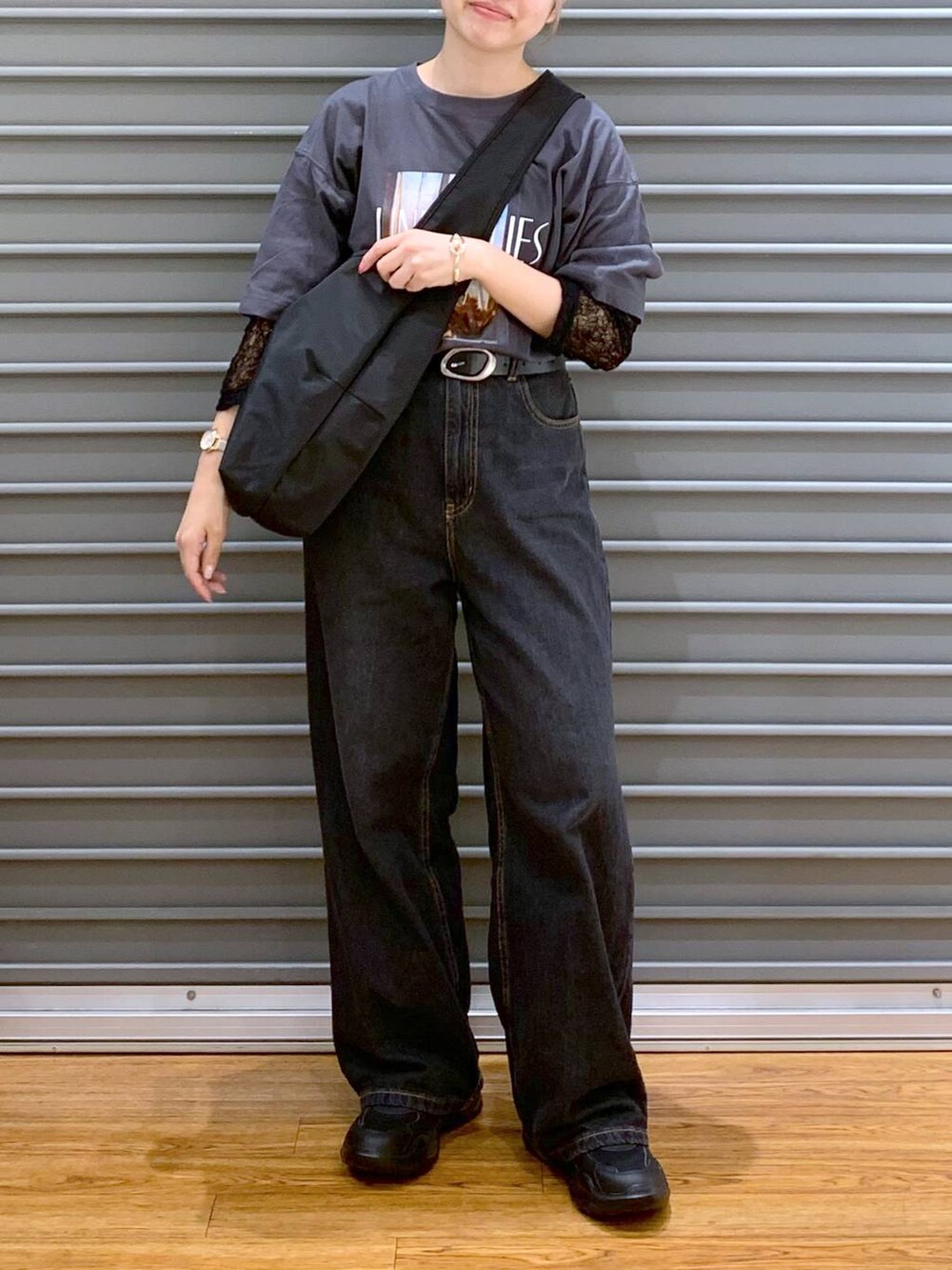 ブラック系のデニムパンツ、ブラック系のスニーカー、ブラック系のショルダーバッグを着用したレディースの秋コーディネートの7枚目の写真