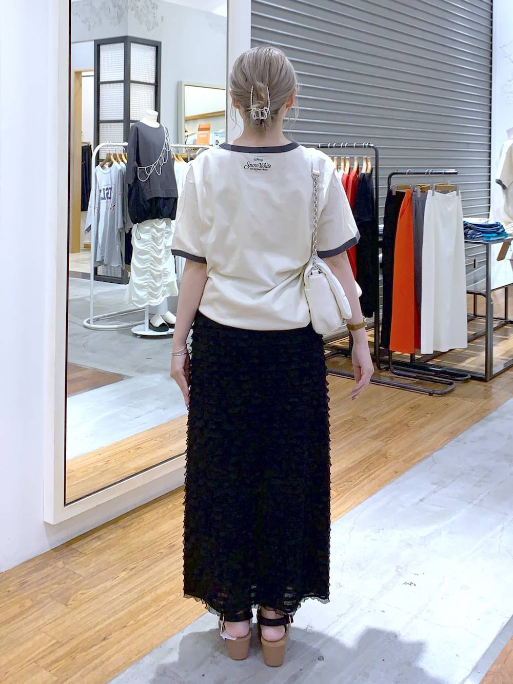 ホワイト系のショルダーバッグ、ブラック系のスカート、ブラック系のサンダルを着用したレディースの夏コーディネートの2枚目の写真