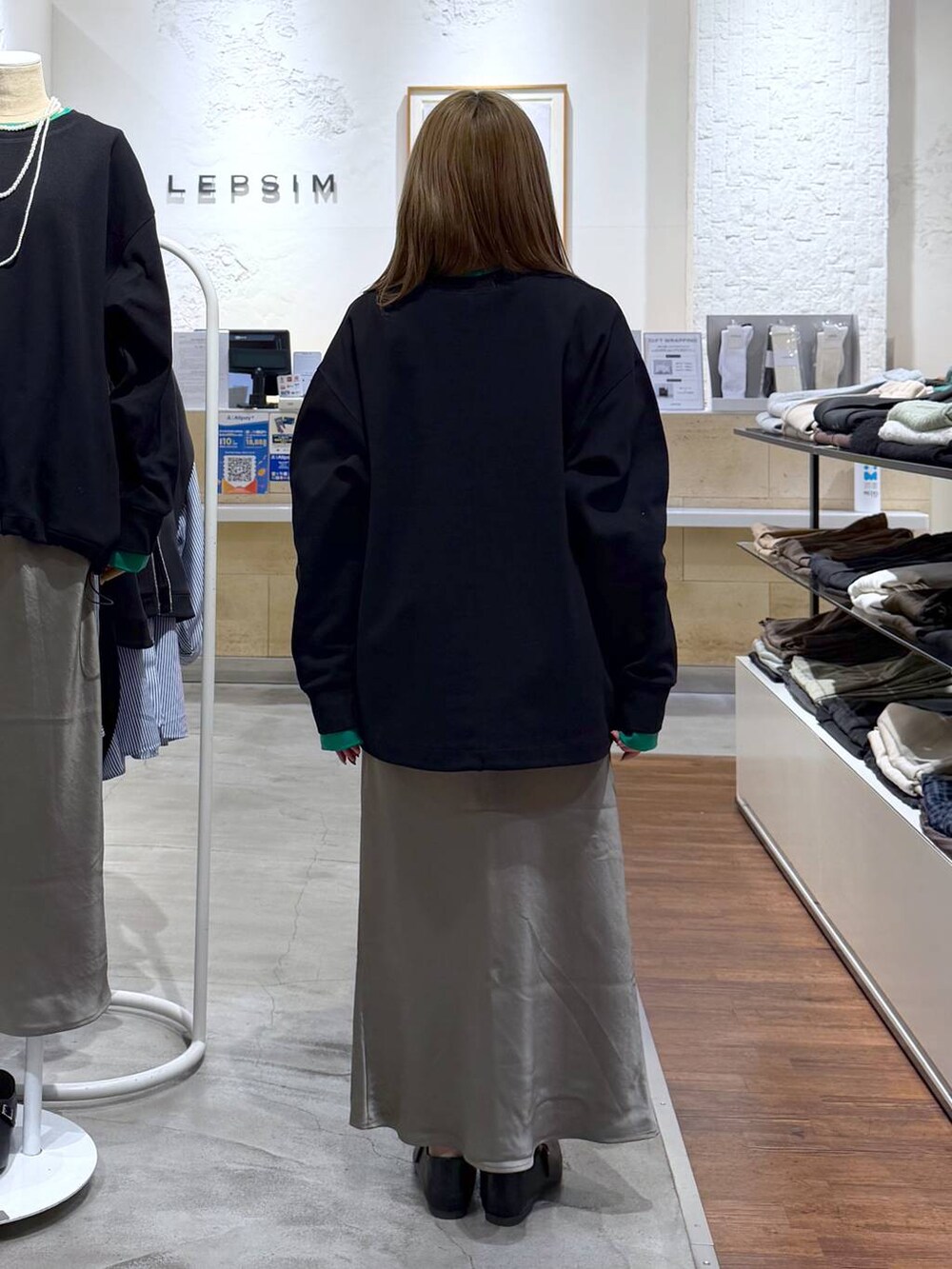 グリーン系のスカート、ブラック系のボストンバッグ、ブラック系のTシャツ/カットソーを着用したレディースの冬コーディネートの2枚目の写真