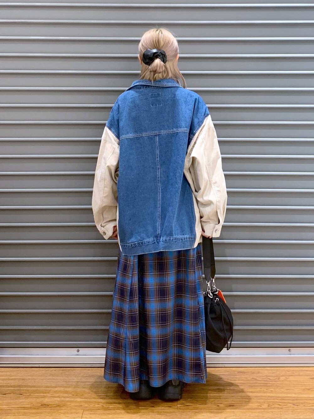 ブラック系のショルダーバッグ、ブラック系のスニーカー、ブルー系のカバーオールを着用したレディースの秋コーディネートの2枚目の写真