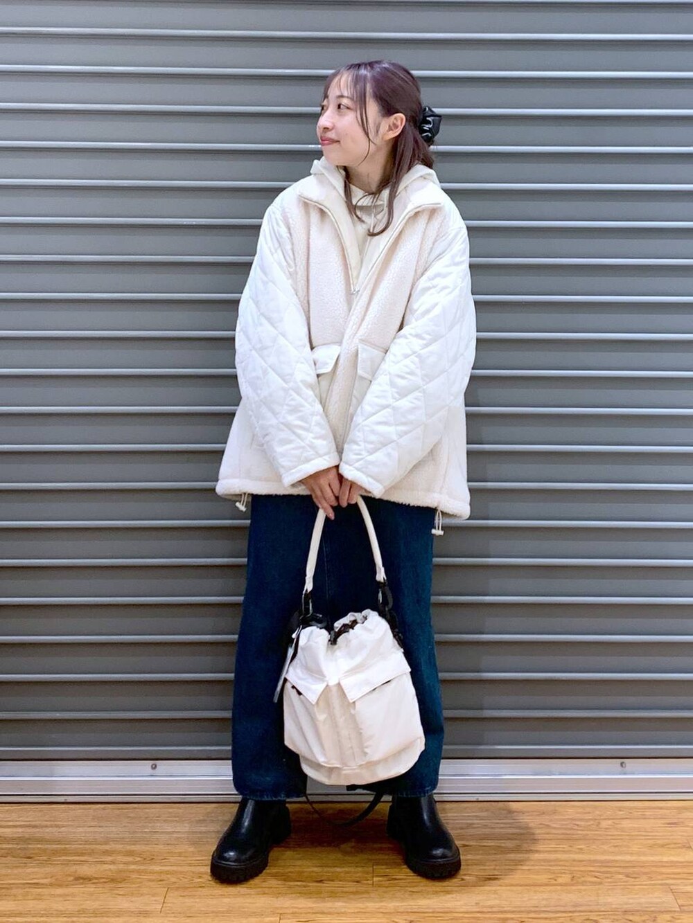 ホワイト系のショルダーバッグ、ブルー系のジャンパースカート、ブラック系のブーツを着用したレディースの冬コーディネートの5枚目の写真