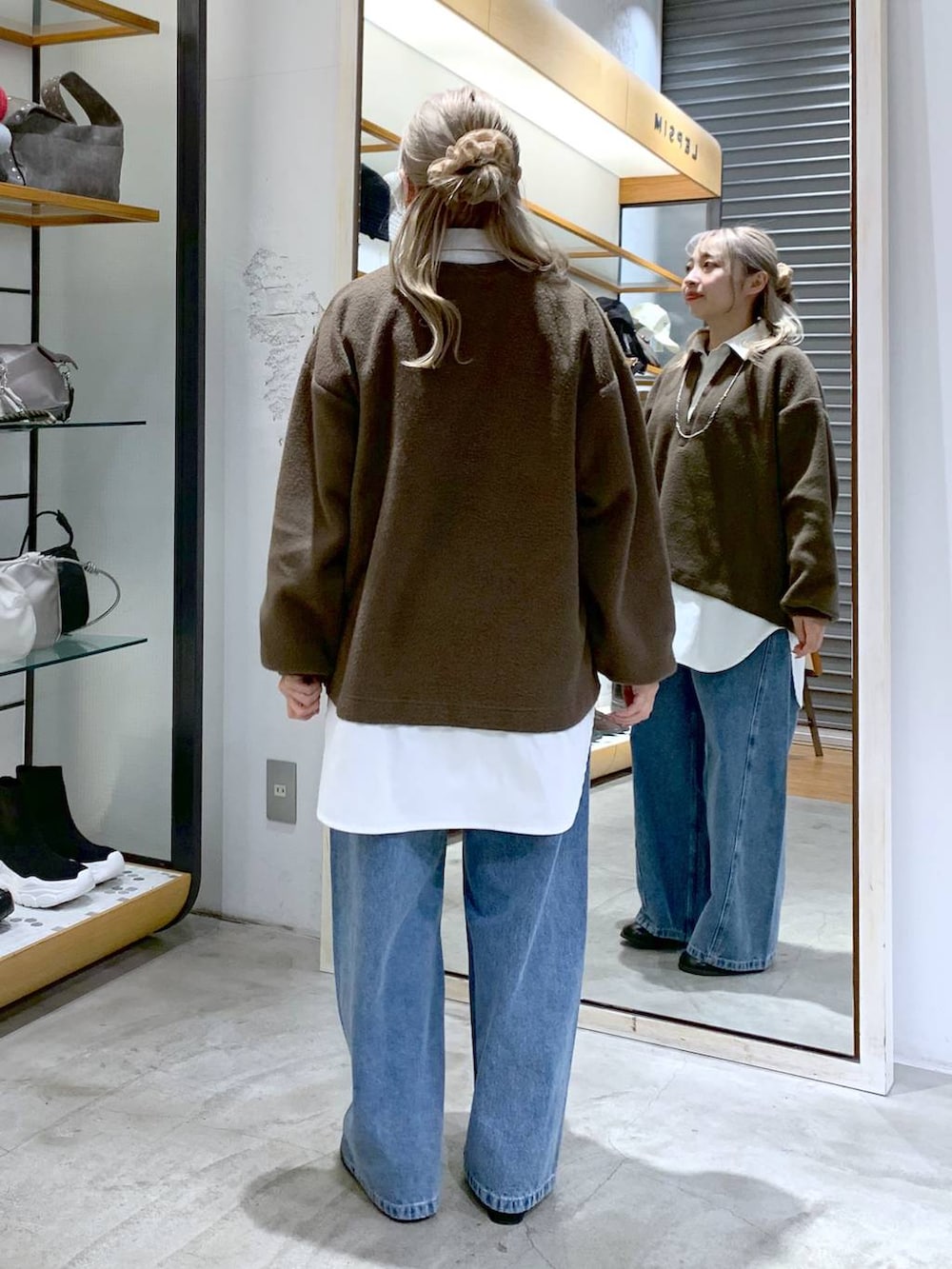 ブラック系のショルダーバッグ、ブラック系のブーツ、ブルー系のデニムパンツを着用したレディースの冬コーディネートの2枚目の写真