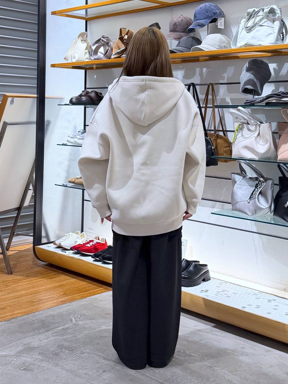 ブラック系のサンダル、グレー系のボストンバッグ、ホワイト系のパーカーを着用したレディースの春コーディネートの2枚目の写真