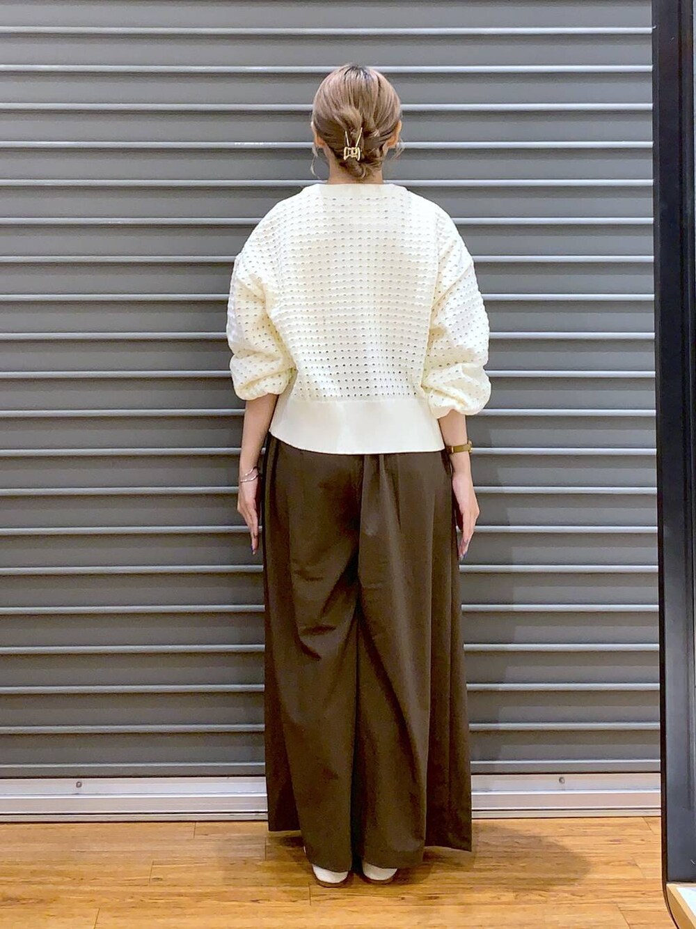 ブラウン系のスラックス、ホワイト系のパンプス、ブラック系のボストンバッグを着用したレディースの秋コーディネートの2枚目の写真