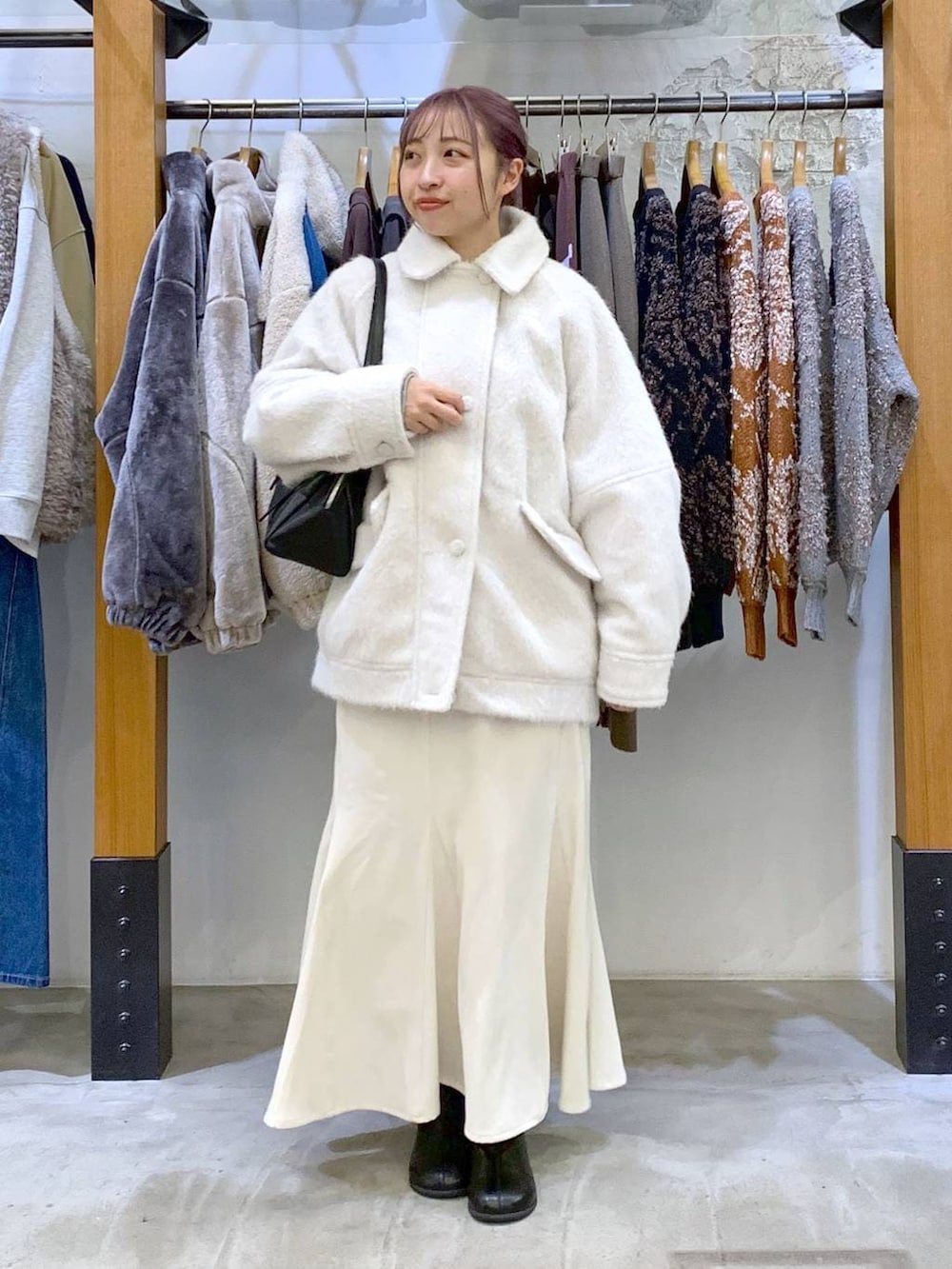 ブラック系のボストンバッグ、ブラック系のブーツ、ホワイト系のブルゾンを着用したレディースの冬コーディネートの7枚目の写真