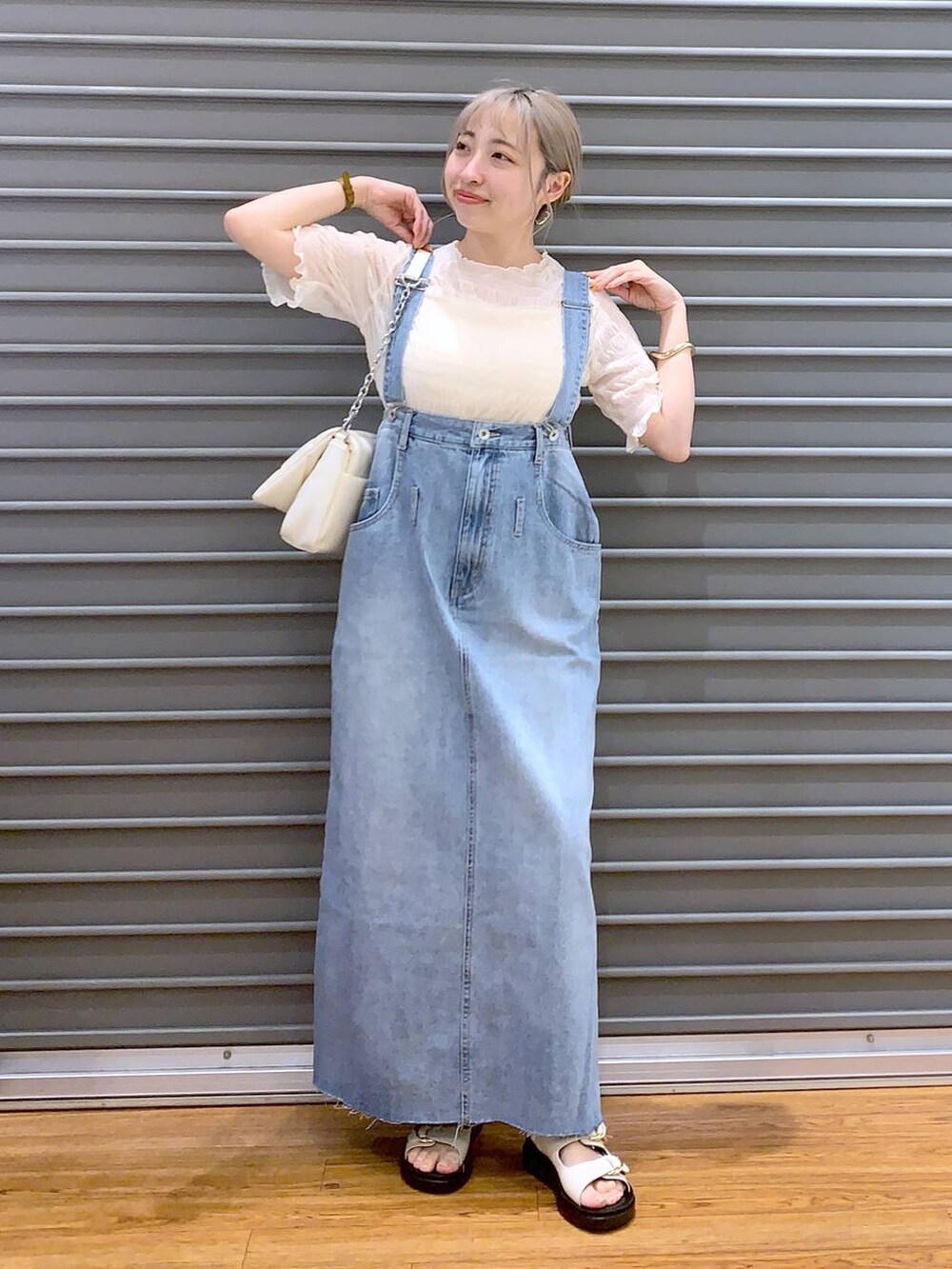 ホワイト系のショルダーバッグ、ホワイト系のキャミソール、ブルー系のジャンパースカートを着用したレディースの春コーディネートの5枚目の写真