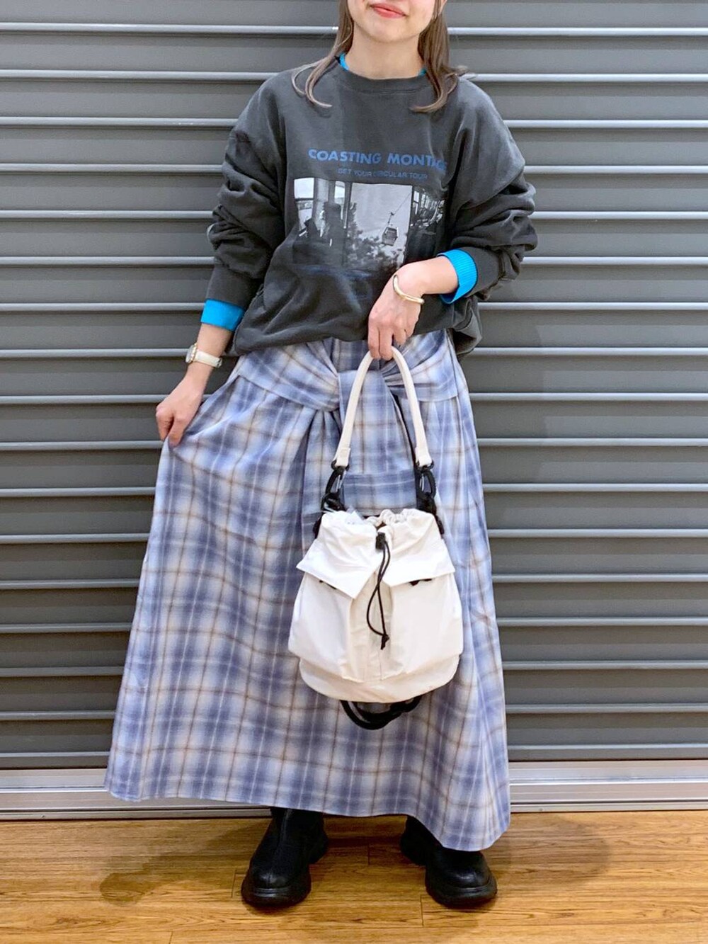 ホワイト系のショルダーバッグ、ブラック系のブーツ、ブルー系のスカートを着用したレディースの春コーディネートの3枚目の写真