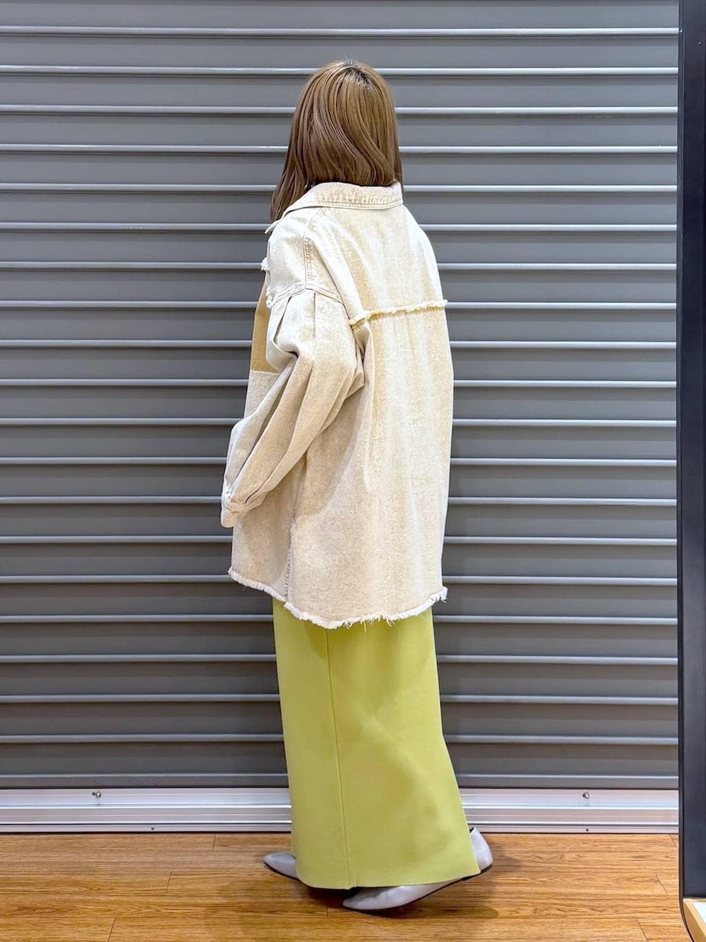 グリーン系のスカート、シルバー系のパンプス、ホワイト系のトートバッグを着用したレディースの春コーディネートの3枚目の写真