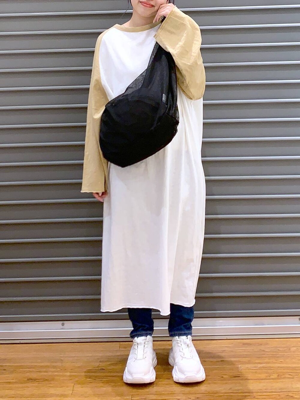 ベージュ系のワンピース、ホワイト系のスニーカー、ブルー系のデニムパンツを着用したレディースの春コーディネートの5枚目の写真