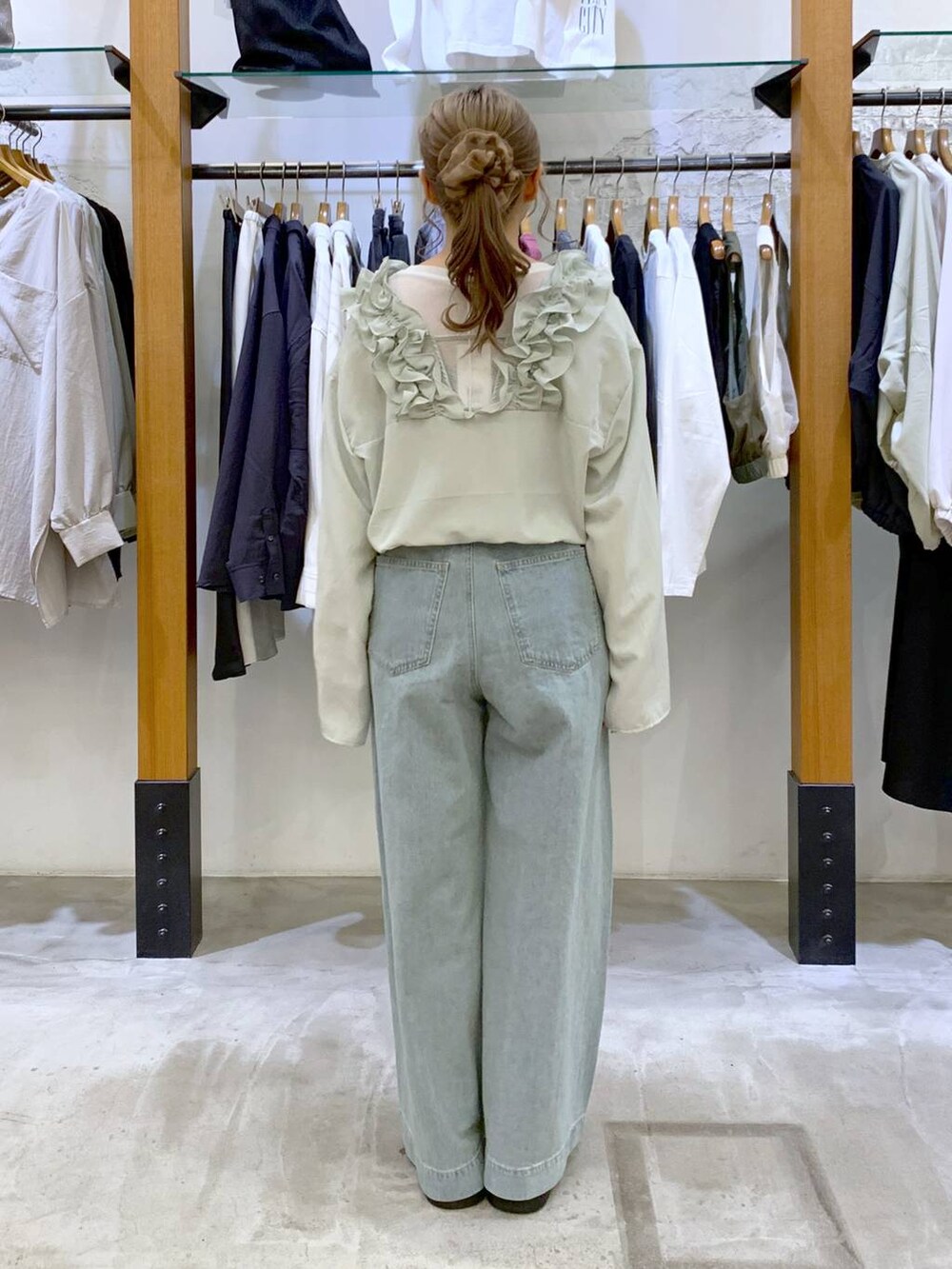 グリーン系のショルダーバッグ、ブルー系のデニムパンツ、ブラック系のサンダルを着用したレディースの春コーディネートの2枚目の写真