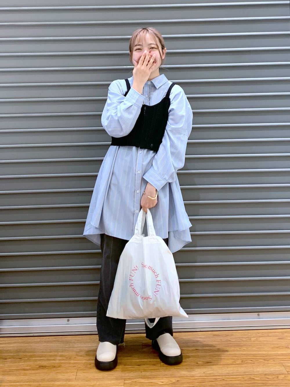 ブラック系のニット/セーター、ブルー系のチュニック、ホワイト系のトートバッグを着用したレディースの春コーディネートの7枚目の写真