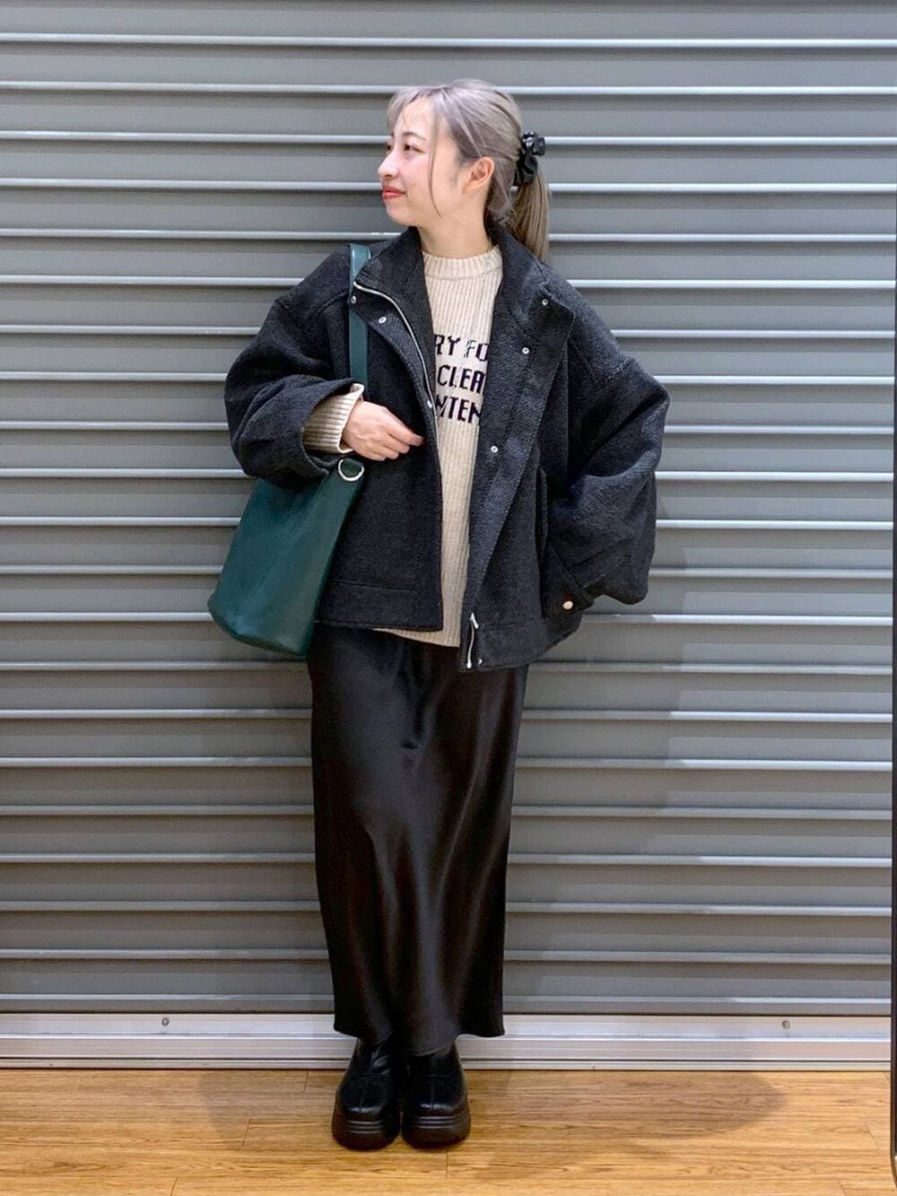 ブラック系のスカート、グリーン系のショルダーバッグ、ブラック系のブルゾンを着用したレディースの冬コーディネートの8枚目の写真