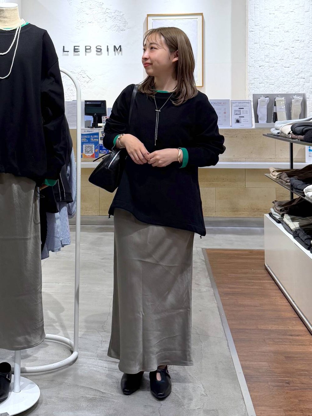 グリーン系のスカート、ブラック系のボストンバッグ、ブラック系のTシャツ/カットソーを着用したレディースの冬コーディネートの4枚目の写真