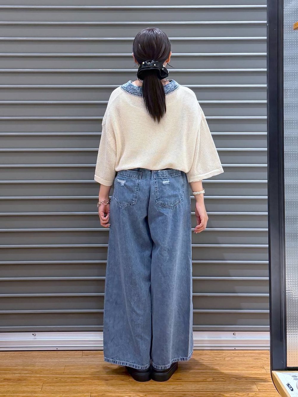 ブルー系のデニムパンツ、ホワイト系のサンダル、ブラック系のショルダーバッグを着用したレディースの夏コーディネートの2枚目の写真