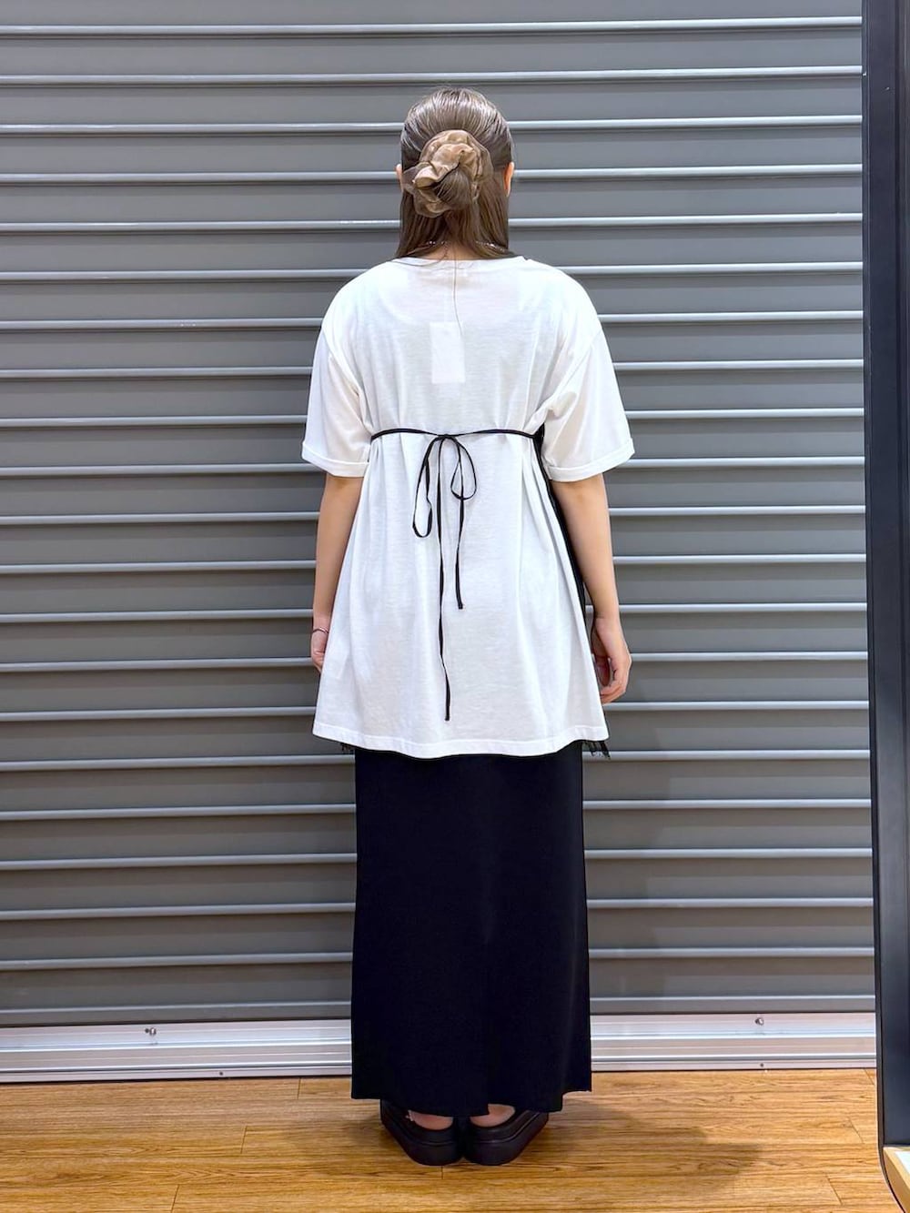 ブラック系のスカート、ブラック系のサンダル、ホワイト系のTシャツ/カットソーを着用したレディースの夏コーディネートの2枚目の写真