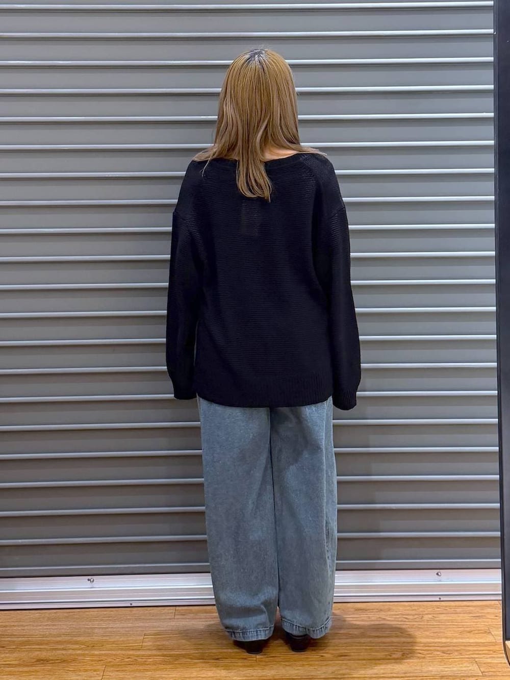 ブラック系のニット/セーター、ブルー系のデニムパンツ、シルバー系のネックレスを着用したレディースの春コーディネートの2枚目の写真