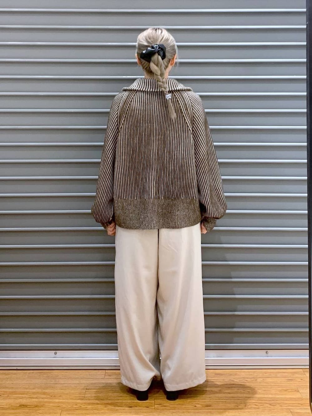 ブラック系のショルダーバッグ、ブラウン系のカーディガン/ボレロ、ブラック系のブーツを着用したレディースの冬コーディネートの2枚目の写真